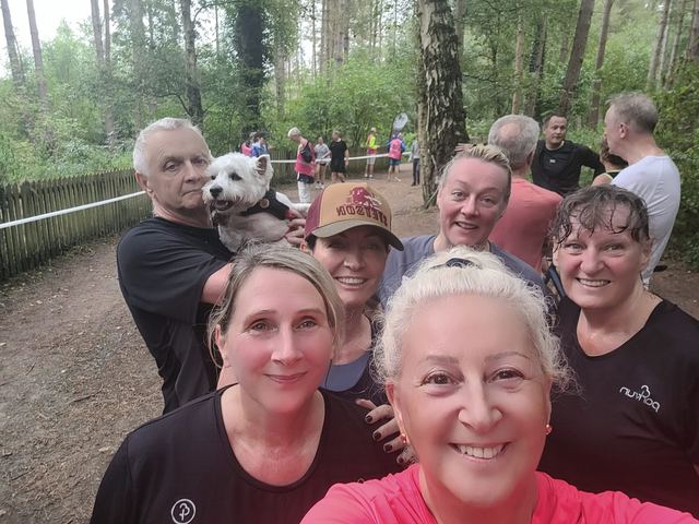 Group selfie of smiling club runners in woodland