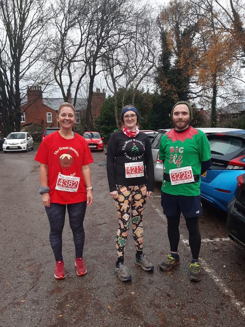 Three runners in festive tops wearing race numbers