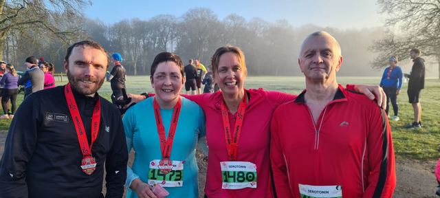 Four runners wearing finisher medals