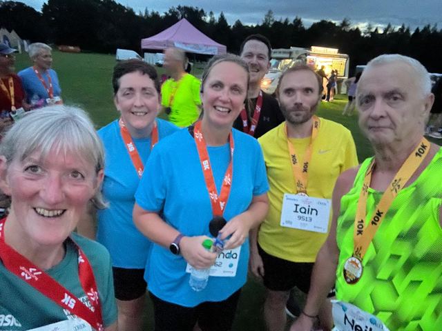 Group selfie of runners with finisher medals at an event