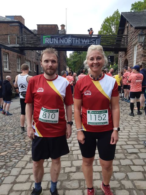 Two runners in red club vests at a Run North West event