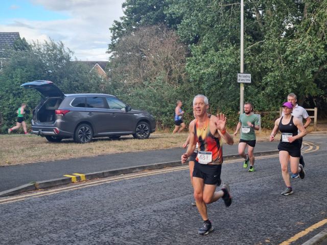 Runners on a road near parked cars